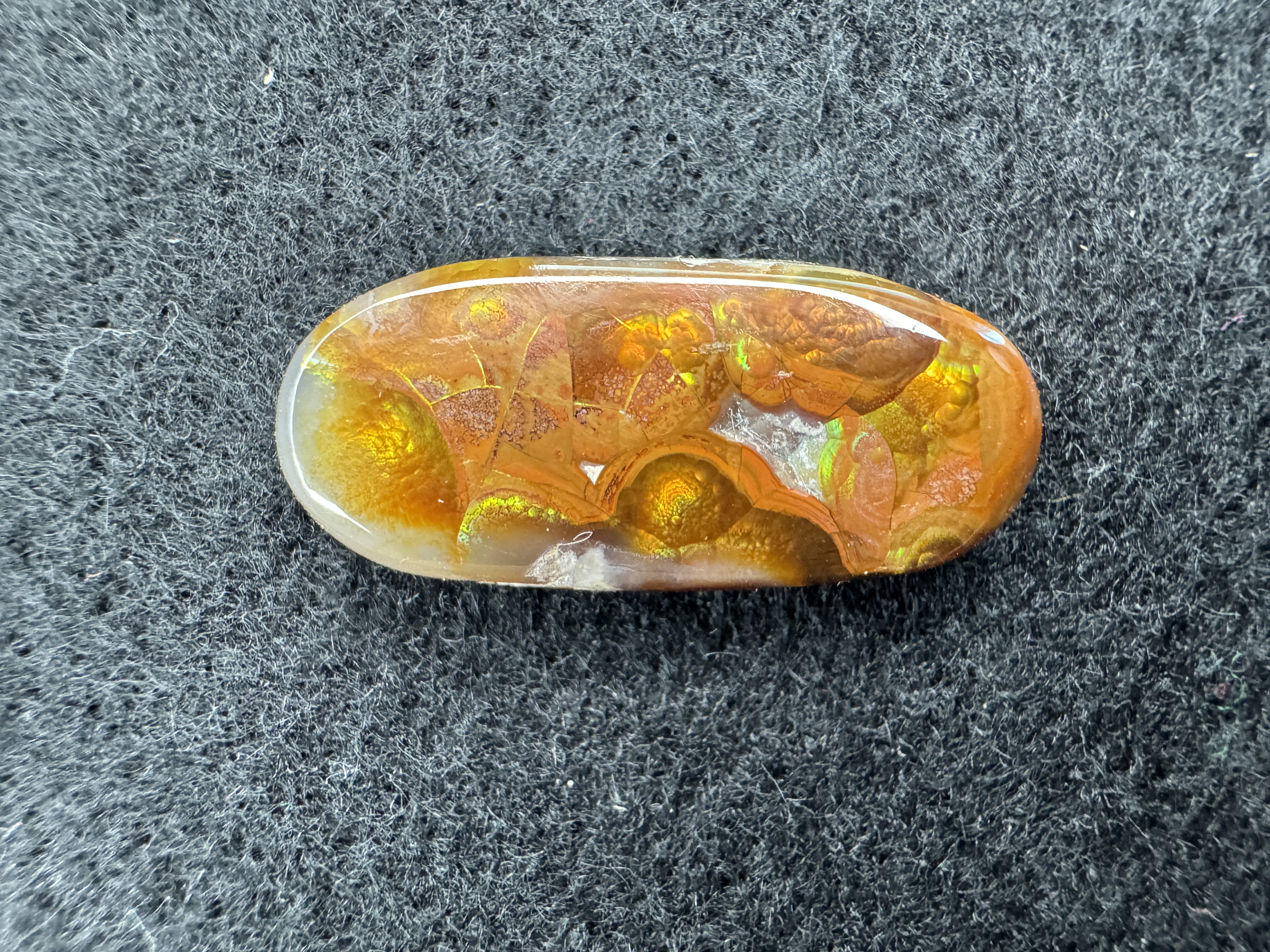 Large, freeform fire agate cabochon with vibrant colors and unique patterns. This cabochon is carved to enhance its natural beauty making for an uneven yet beautifulsurface.