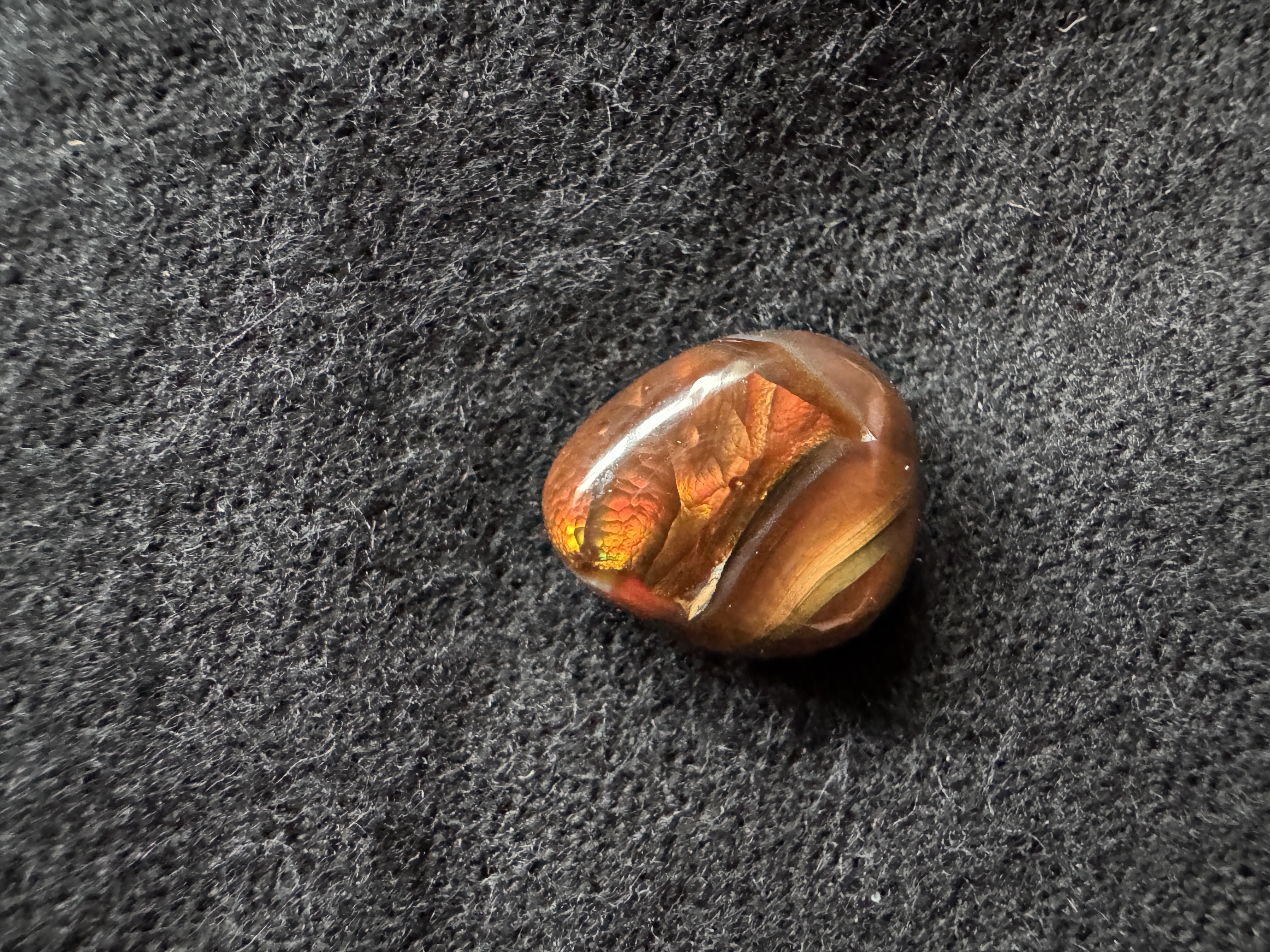 Fire agate freeform cabochon with vibrant orange, red, and iridescent flashes. Unique polished gemstone for jewelry making.